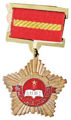 新疆维吾尔自治区“五好职工”奖章的颁发年代为1963年,用途为佩饰。奖章重量为2克,最宽4 厘米,厚 0.2 厘米,通长 7 厘米。该奖章由两部分组成,上半部为红底黄色斜纹绶带,奖章主体部分为五角星状。奖章中间为圆形,圆形内部上方有五角星,下方白色书本形状中,有“五好职工”字样。